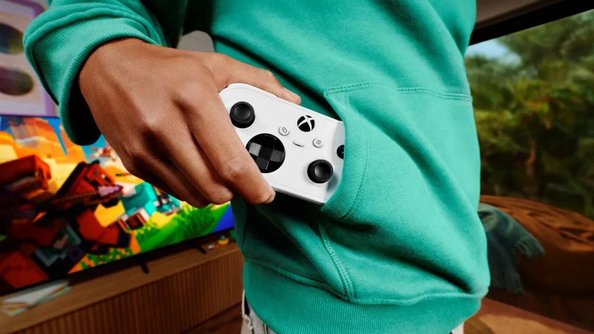 Yeşil kapüşonlu üstünün cebine beyaz Xbox Nano kontrolcüsü koyan oyuncu